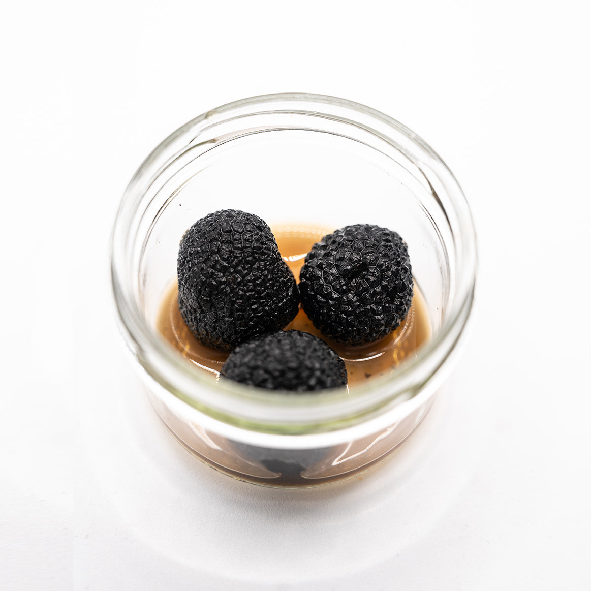 Truffes noires entières Tuber Melanosporum du Périgord dans leur jus - gros plan bocal Origine Truffe